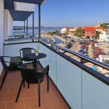Balcony with a small table and a view of the street and the sea
