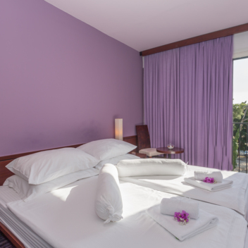 Hotel room with purple walls, double bed and balcony