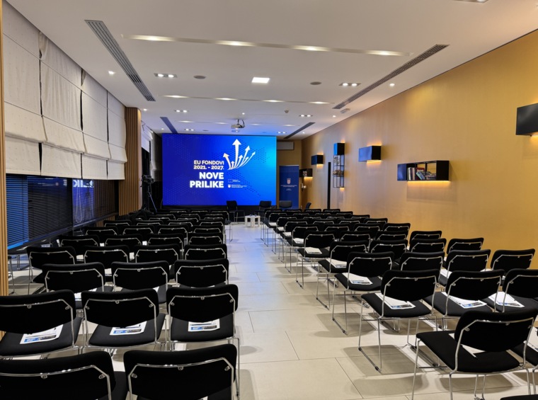 sala conferenze con grande schermo e file di sedie