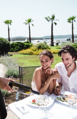 A waiter serving dessert to a couple at an outdoor table